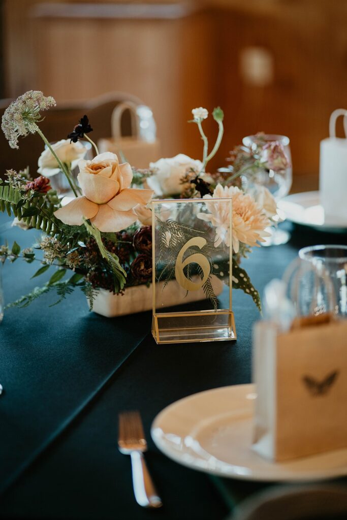 Wedding reception table decor with cream, green, and burgundy wedding flower arrangements