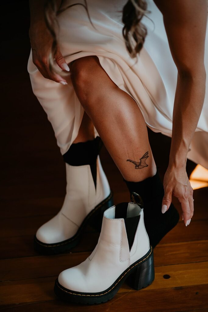 Bride putting on white heeled Doc Marten boots for her Thunder Island wedding