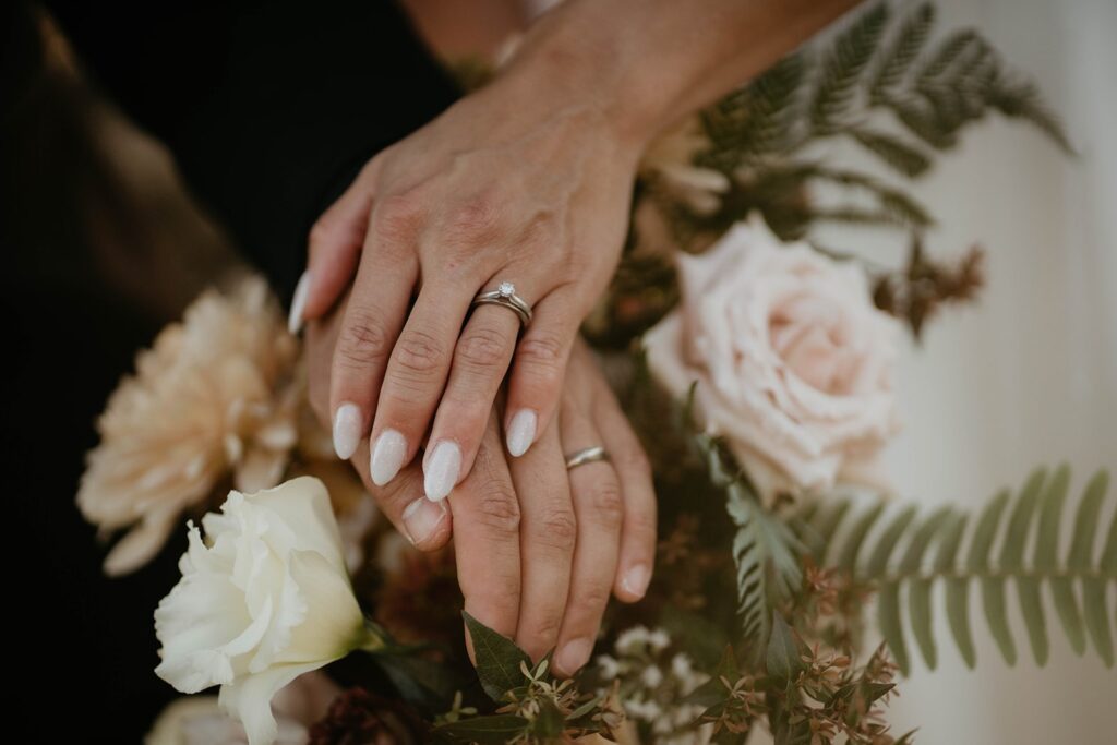 Bride and groom resting hands on wedding florals