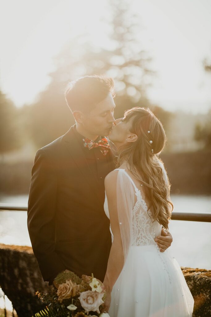 Bride and groom kiss during wedding portraits by the Columbia River in Oregon