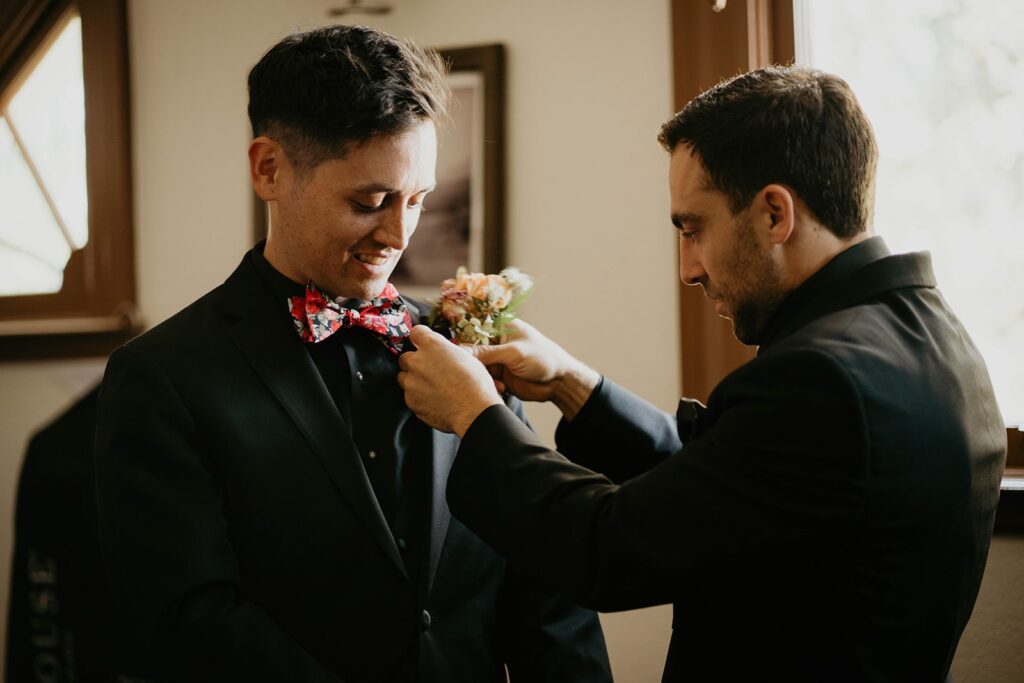 Groomsman helping groom with his bowtie before Thunder Island wedding