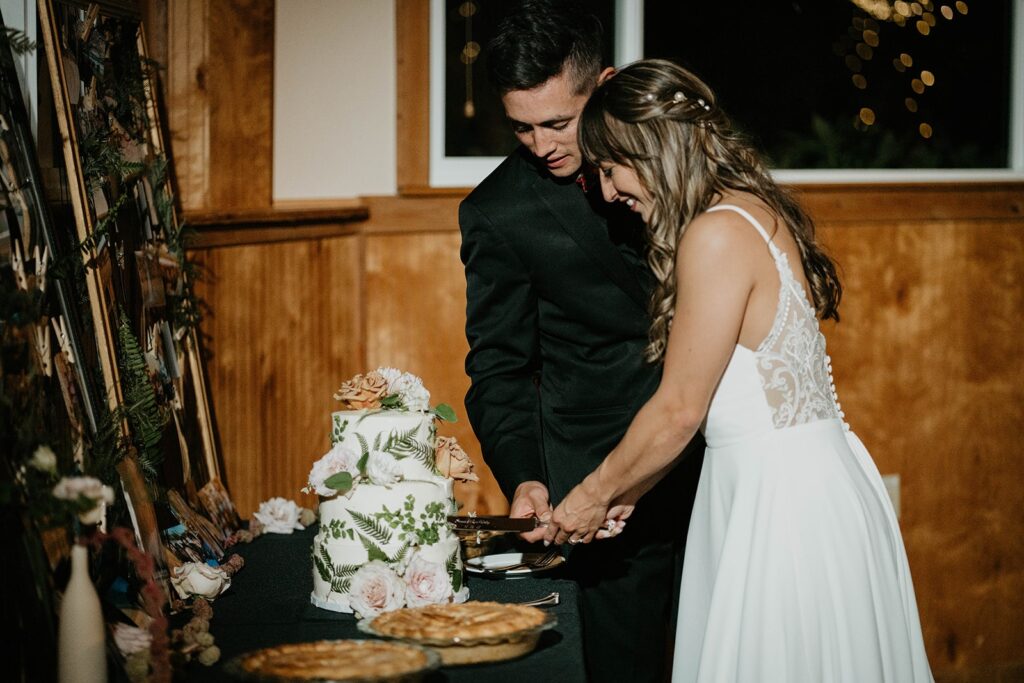 Bride and groom cut three tier wedding cake at Thunder Island wedding reception