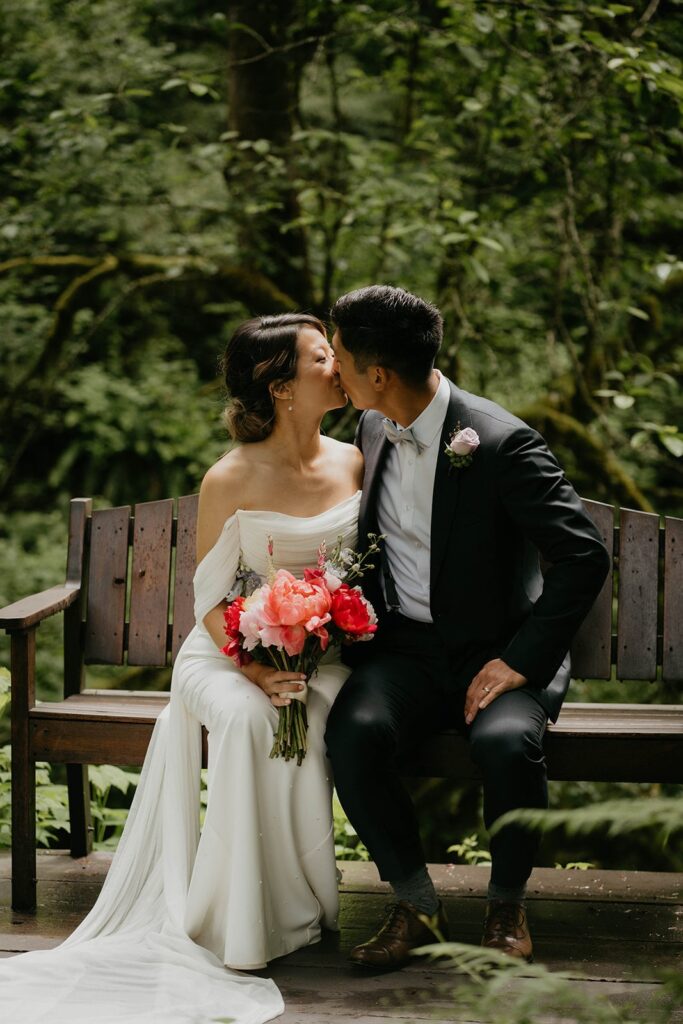 Bride and groom sit on a bench and kiss at Bridal Veil Lakes wedding