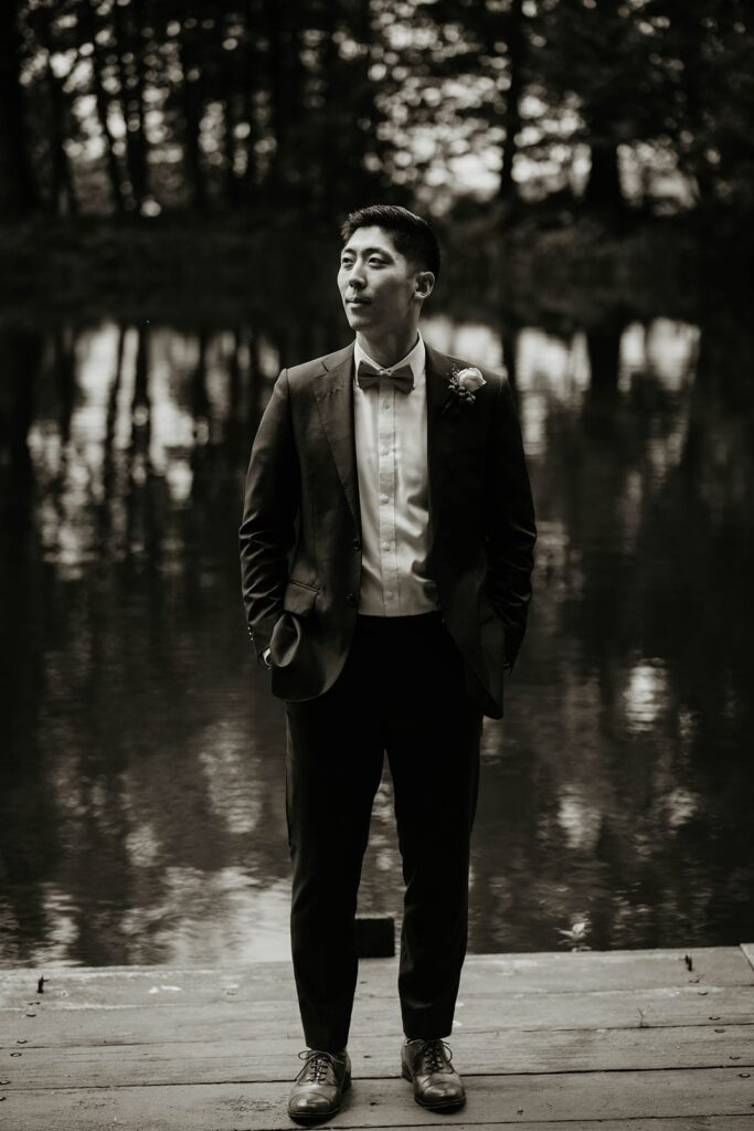 Groom standing by the lake for wedding portraits
