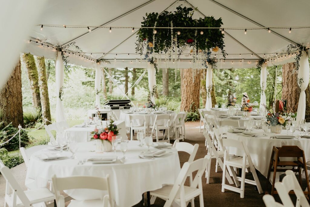 White wedding tables and chair under a tent at Bridal Veil Lakes wedding in Oregon