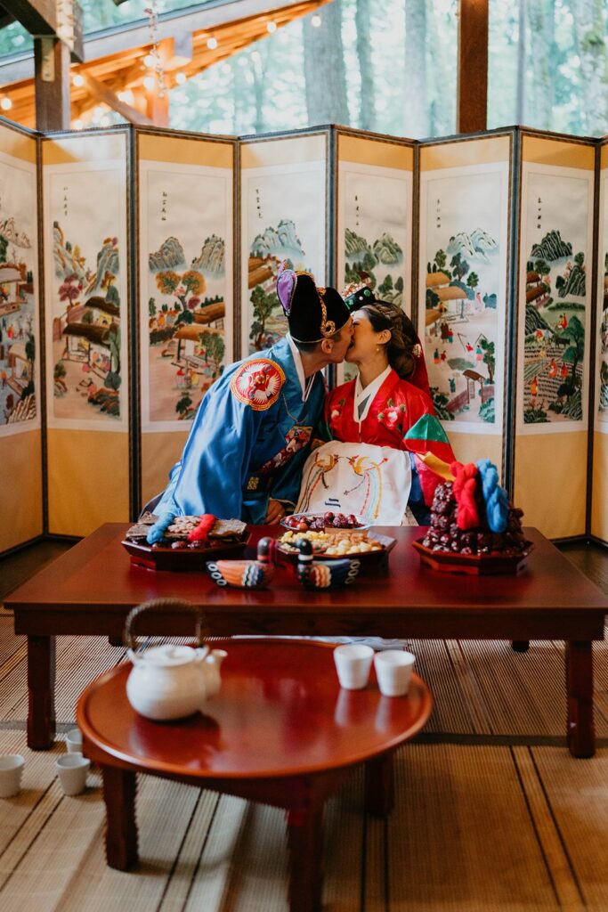 Bride and groom kiss during traditional Korean wedding ceremony