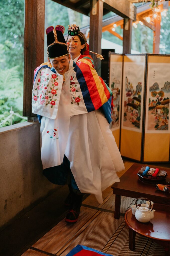 Bride riding piggyback on groom during traditional Korean wedding ceremony