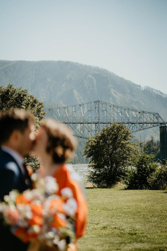 Bride and groom kiss in front of Bridge of the Gods for their Cascade Locks wedding