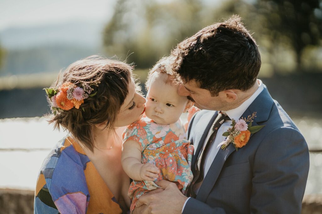 Bride and groom kissing their 1 year old daughter at Cascade Locks wedding
