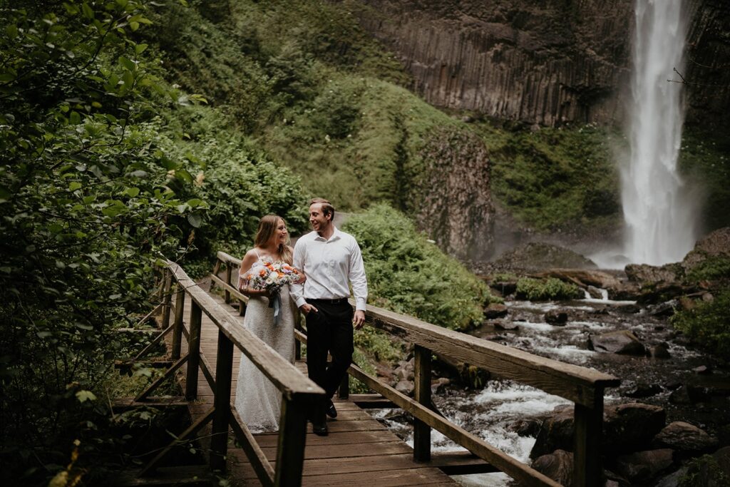 Bride and groom walking across a wood bridge at Latourell Falls elopement
