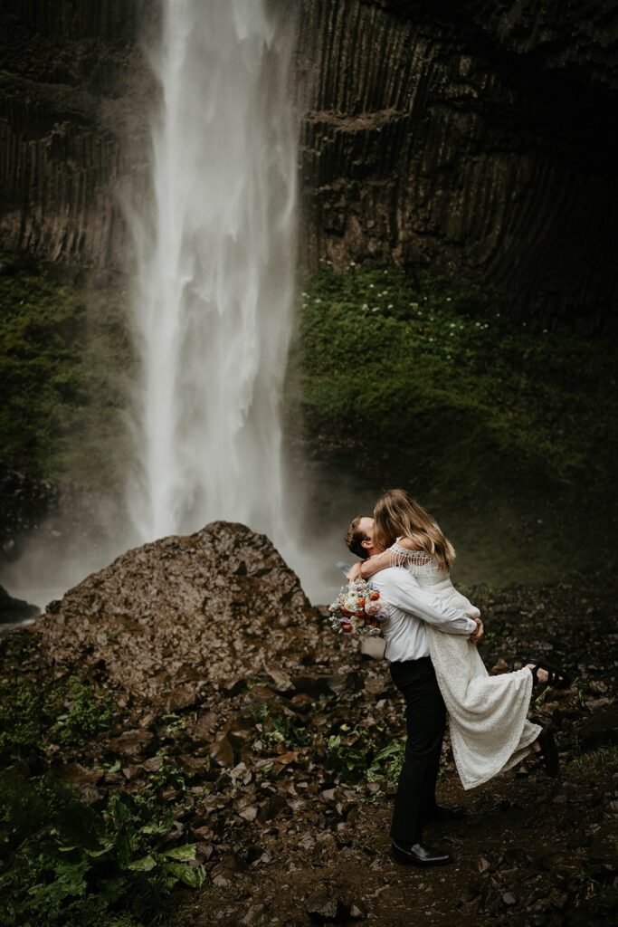 Groom lifts bride and kisses her at Latourell Falls elopement