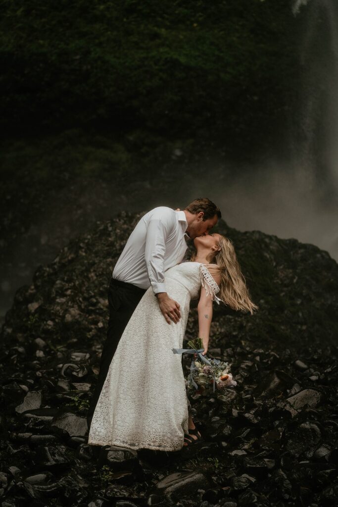 Groom dips bride for a kiss during Oregon elopement portraits at Latourell Falls