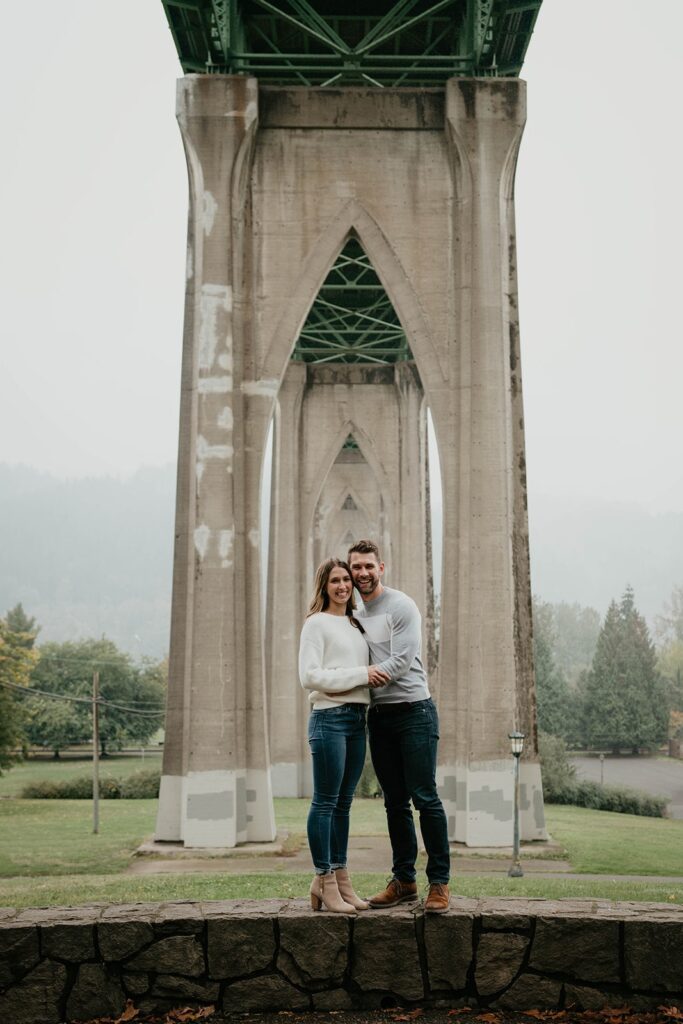 Couple posing for fall engagement photos in Cathedral Park, Oregon