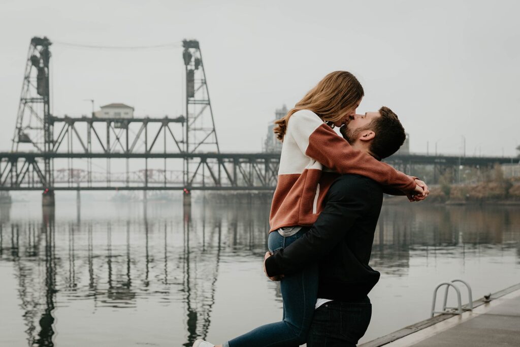 Couple kissing during Portland engagement photo session by the river