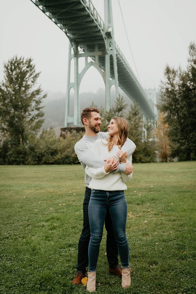 Couple hugging and smiling during Cathedral Park, Oregon engagement photo session