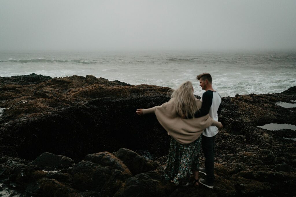 Couple standing in front of Thor's Well during their Cape Perpetua engagement session