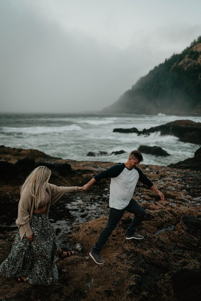 Couple walking on the rocky beach in front of Thor's Well during their Cape Perpetua engagement session