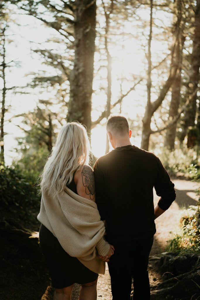 Couple holding hands while walking through the forest during their Cape Perpetua engagement session