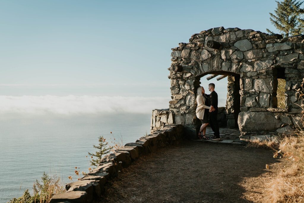 Couple standing at Cape Perpetua viewpoint for their Oregon Coast engagement photos