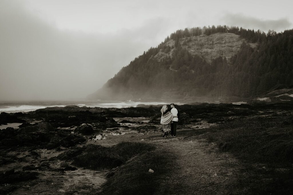 Couple walking down to the ocean during their engagement photos at Cape Perpetua