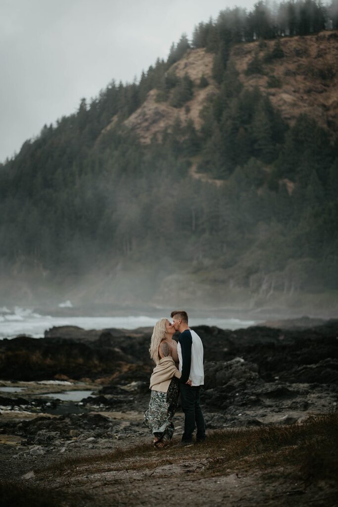 Couple kissing on the rocks at their Cape Perpetua engagement photo session