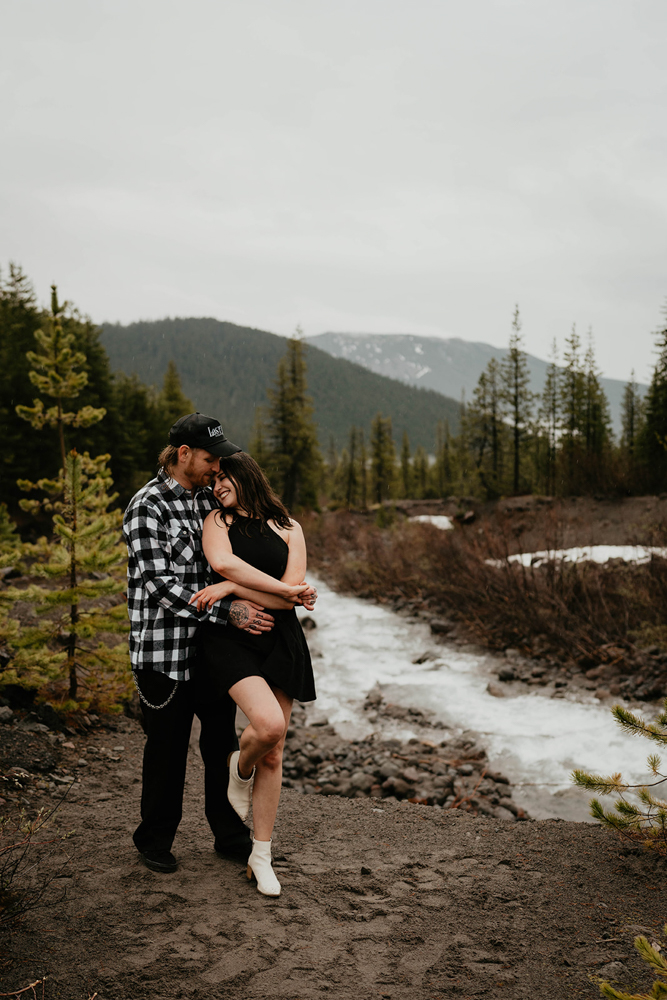 A couple holding each other with rivers and forests in the background at White River West Sno-Park.
