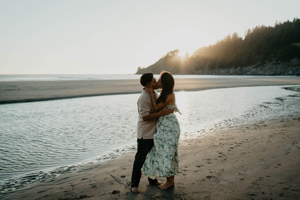 A couple kissing as the sun sets with the beach and forest in the background at Short Sand Beach. 