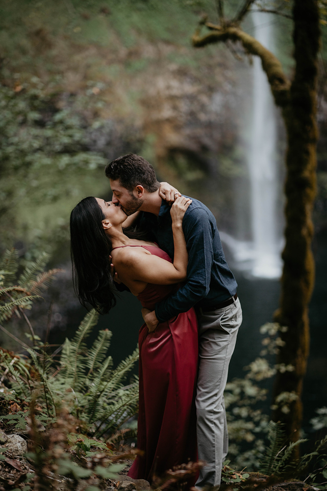 A couple kissing with Silver Falls in the background. 