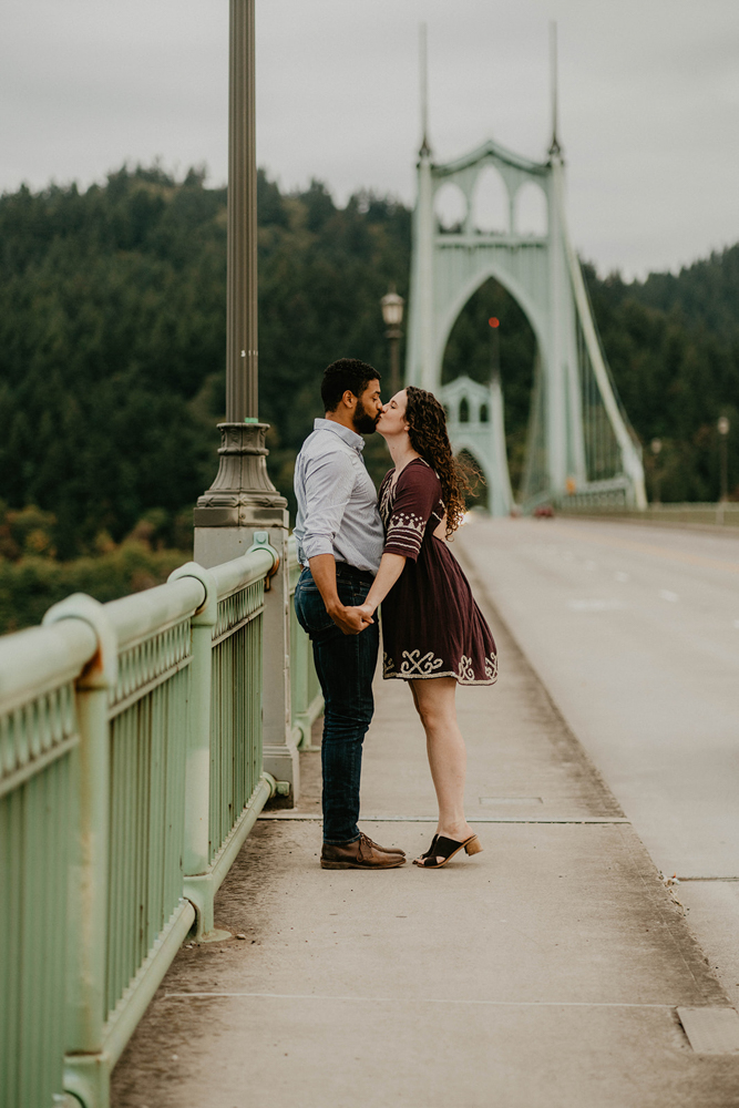 A couple kissing along the railing of St. Johns Bridge in Portland.  