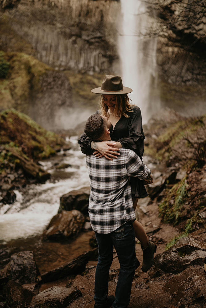 A couple hugging in front of Latourell Falls. 