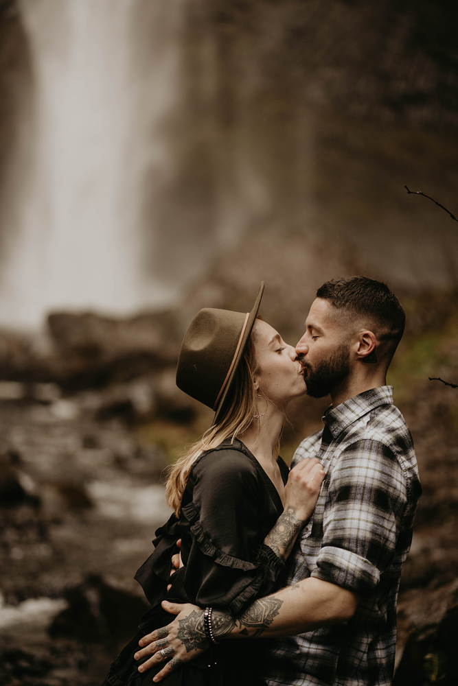A couple kissing in front of Latourell Falls. 