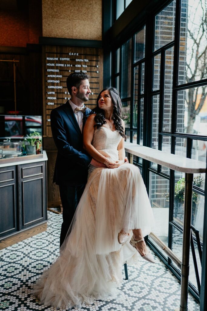 Bride and groom sit at a coffee bar for wedding portraits at their Blockhouse Portland wedding