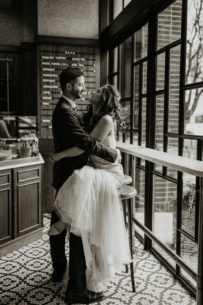 Bride and groom sit and hug at a cafe before their Blockhouse wedding in Portland