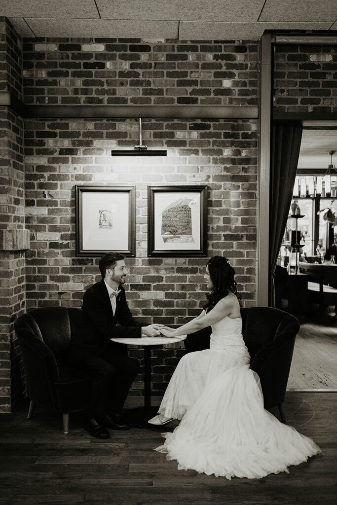 Bride and groom sit at a cafe table during their Blockhouse Portland wedding photos