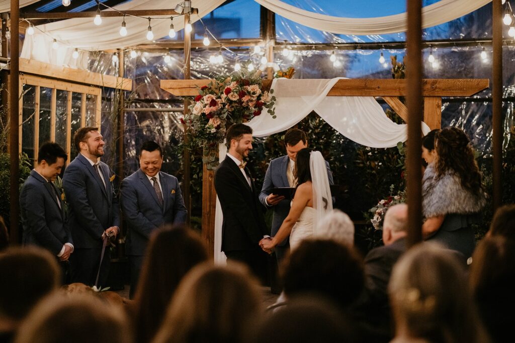 Bride and groom hold hands during their Pomarius Nursery wedding ceremony at Blockhouse PDX
