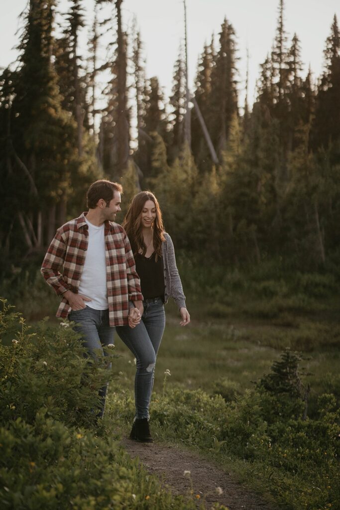 Couple holding hands walking through a hiking trail at their Mt Rainier engagement