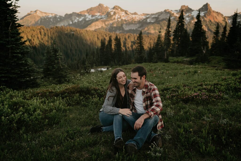 Couple sitting and laughing in the grass at their Paradise, Mt Rainier engagement photos