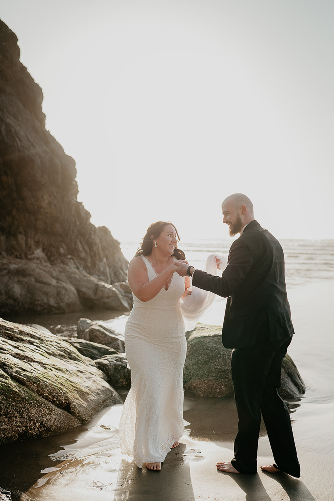 The bride and groom dancing on the sand by a sea stack at Cannon Beach. 