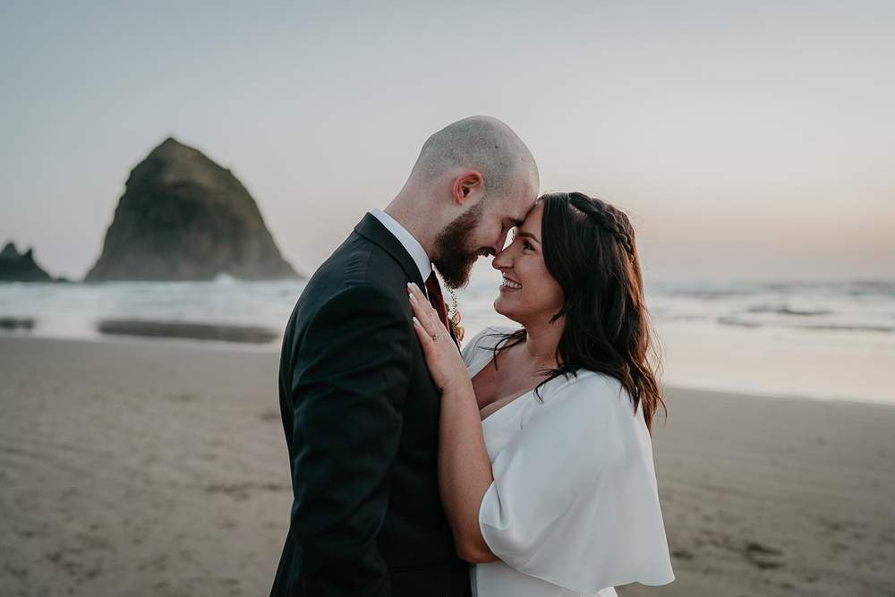 The newlyweds embracing each other  with Haystack Rock in the background at Cannon Beach. 