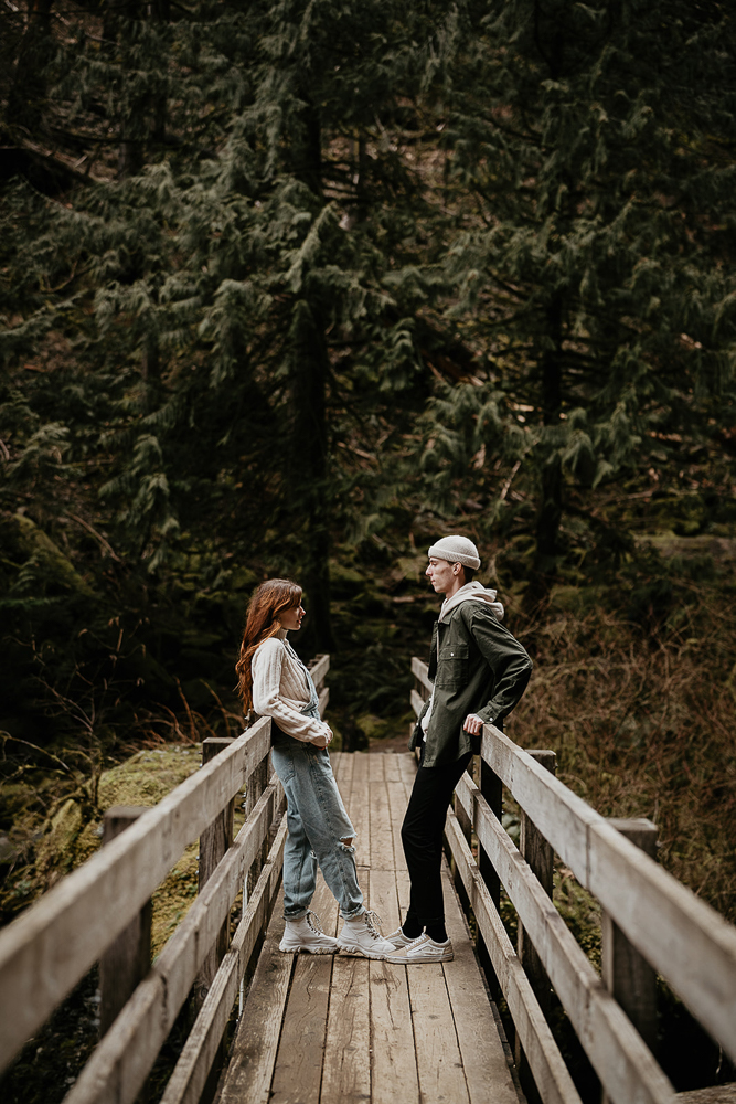 A couple leaning against either side of a bridge railing at the Columbia River Gorge. 