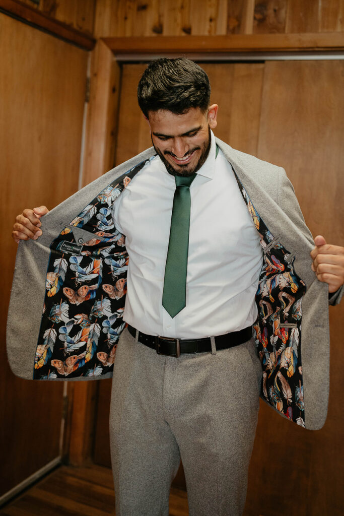 The groom showing off his feather and butterfly prints on the inside of his blazer. 
