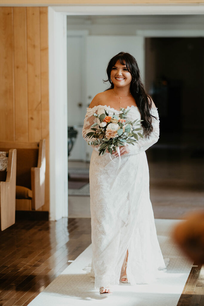The bride walking down the isle holding a bouquet of flowers. 