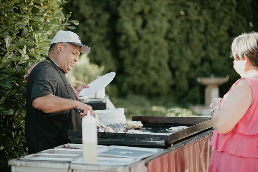 A man serving tacos to guests. 