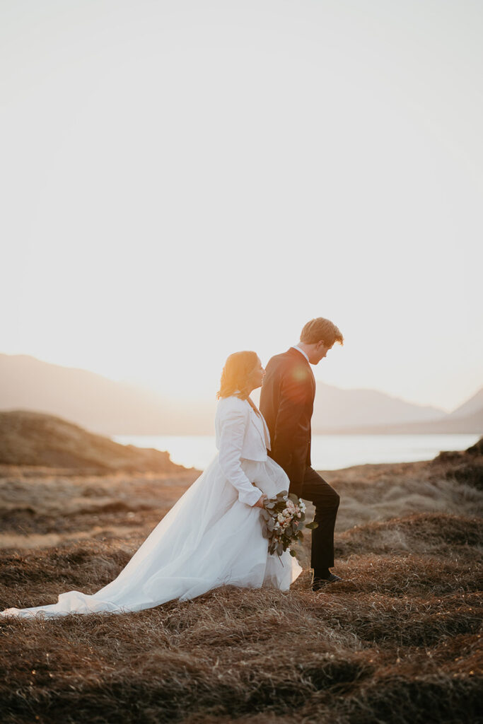 A bride and groom walking along a field while the sun sets in Iceland during their elopement. 