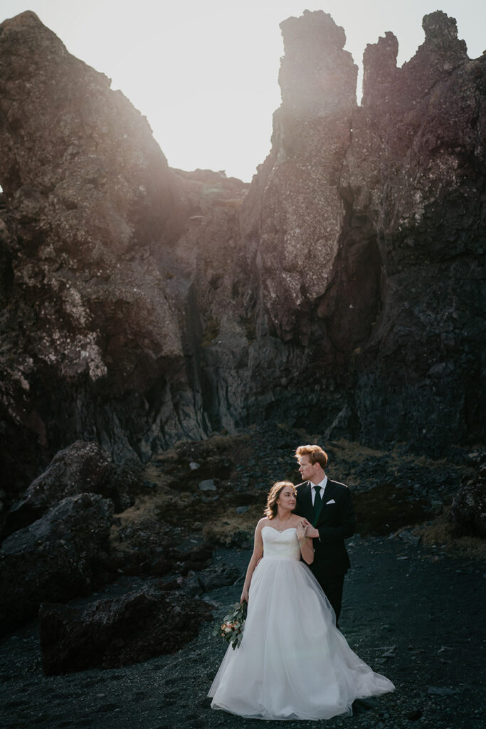 A couple posing with large sea cliffs in the background in Iceland. 