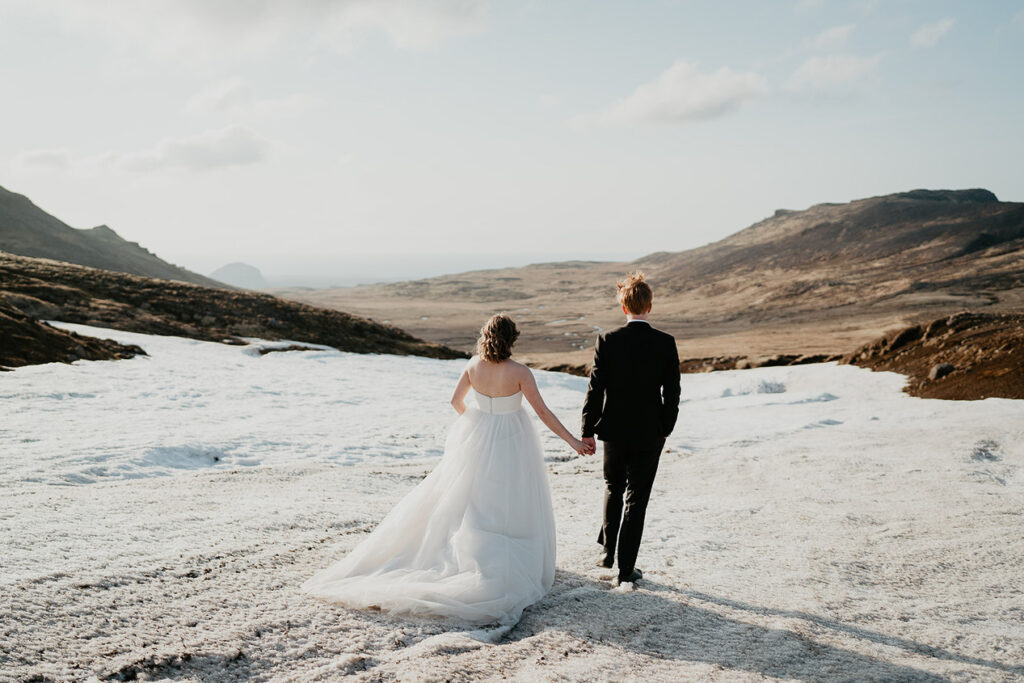 A bride and groom walking along a field of white sand while on their Iceland elopement. 