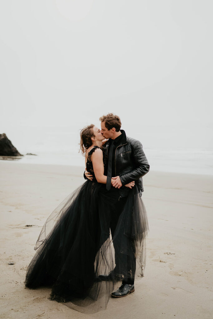 A couple kissing while standing on the beach. 