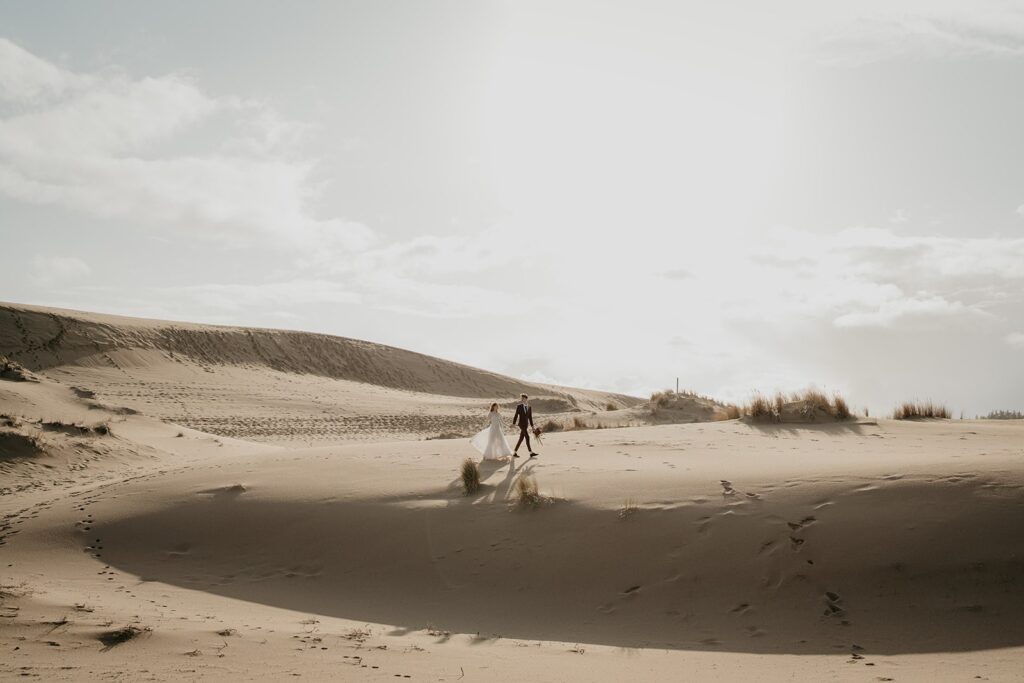 Bride and groom walk across the sand during their Oregon sand dunes elopement