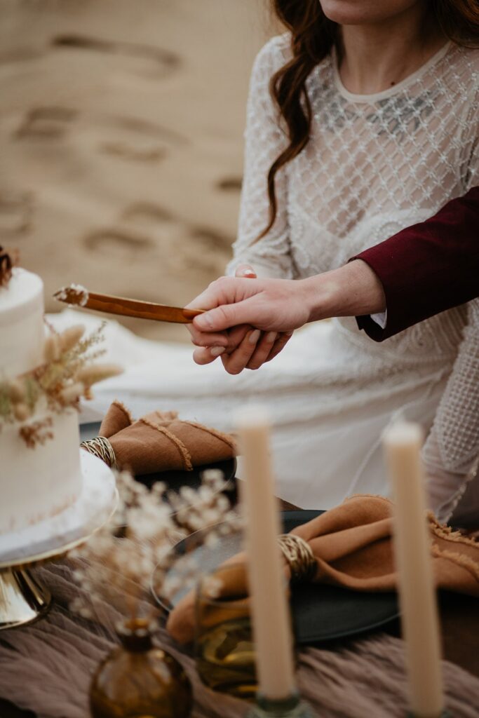 Bride and groom cut cake during their Oregon sand dunes elopement