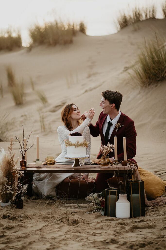 Bride and groom feed each other cake during their Oregon sand dunes elopement
